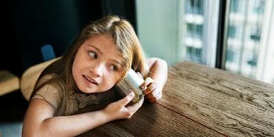 girl listening on a tin can telephone