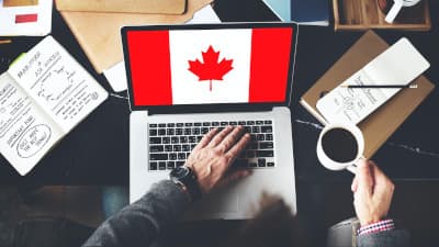 man looking at computer with Canadian flag on screen