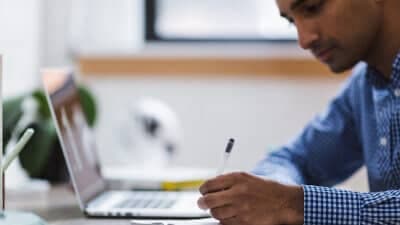 Man taking notes with laptop