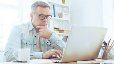 Man reading on laptop and thinking