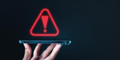 A hand holding a phone with a warning