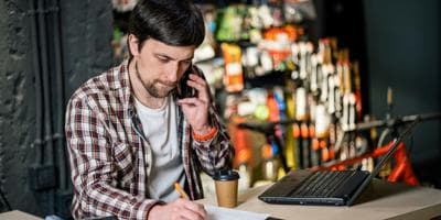 A shop owner talking on a phone with a customer