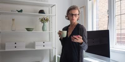 woman with coffee cup looking at mobile phone