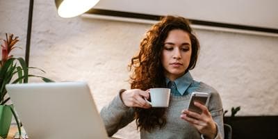 a woman drinking coffee and looking at her phone